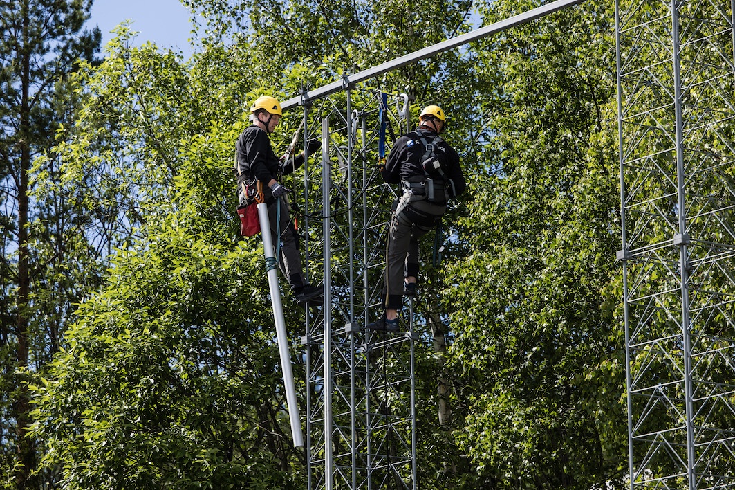To ansatte klatrer opp i en treningsmast for å øve på hvordan de skal jobbe ute i felt.