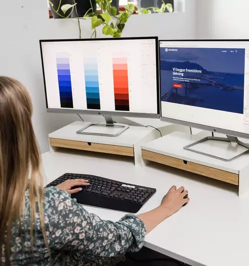 Ansatt sitter foran en PC og jobber med farger til en kunde.