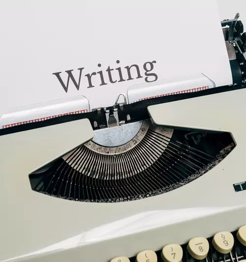 Gammel skrivemaskin, hvor det er at ark det står Writing på (skrive på norsk).