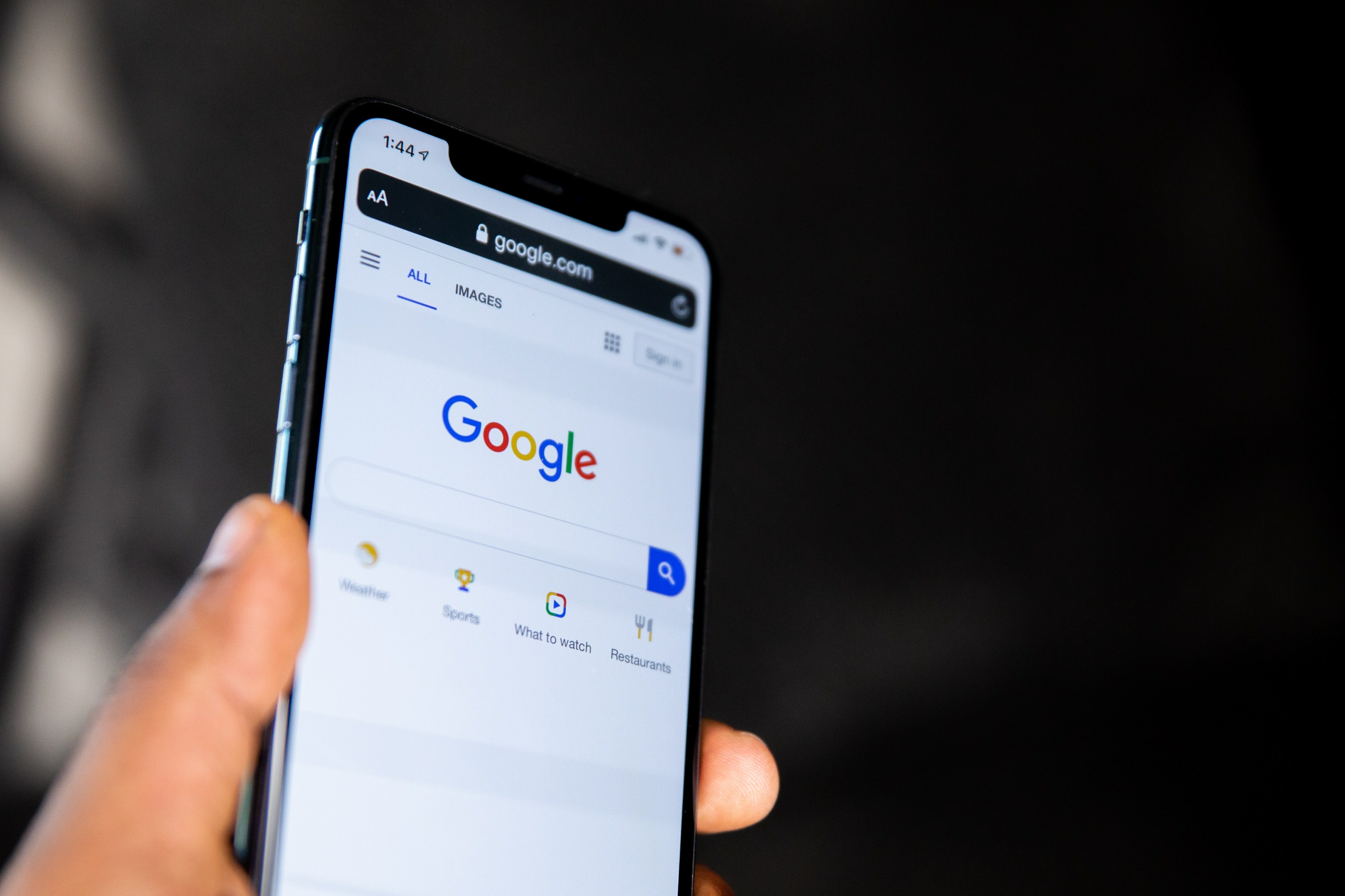 En mobil blir holdt opp og viser frem Google søkefelt.